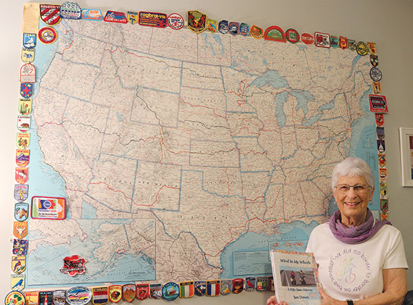 Jan Down stands by map holding a book